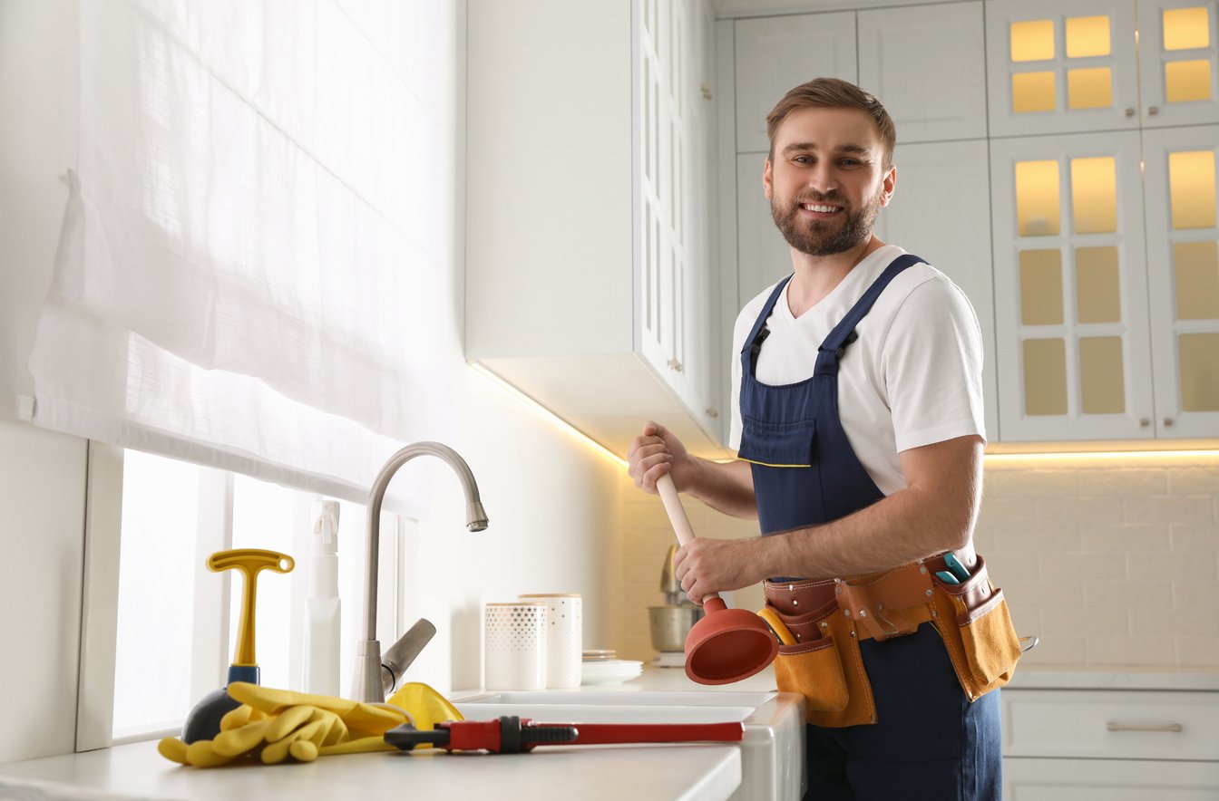 Plumber with Plunger near Clogged Sink in Kitchen