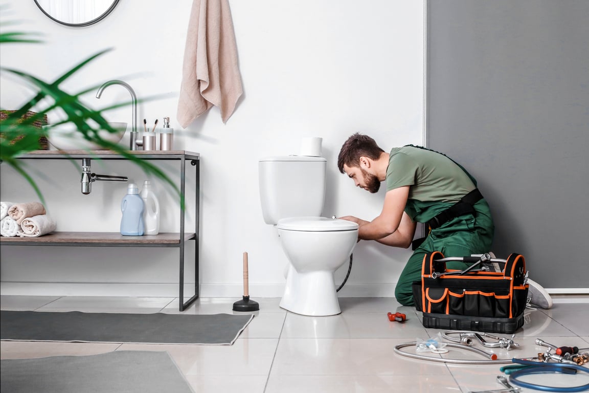 Plumber Installing Toilet Bowl in Bathroom